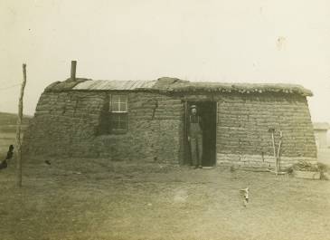 McKenzie County 1910 - Pioneer Museum of McKenzie County Collection - Man standing in doorway of sod house (postcard) 