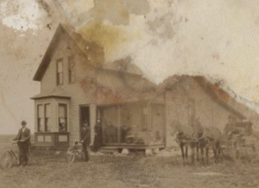 Munich 1900 - SHS Gudmundur Grimson Papers - George Sjirvat, Emma Sjrvat, and a man identified as a preacher stand in front of a house, likely in the Munich, N.D. area. Emma stands on the porch, while two of the men stand with bicycles, and a third man sits in a carriage drawn by two horses. 