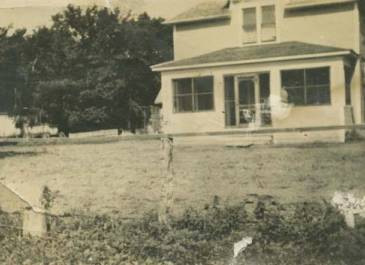 Pembina 1935-36 - A view of Governor Walter Welford's house in Pembina. The house has a screened-in front porch, and a cart is visible in the side yard.
