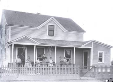 Hirschville - Farm home with front porch. A picket fence is in front of the home. Family members are on the porch. Dickinson Museum Center
