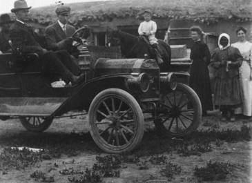 SHS Agnes Fisher Photograph Collection - Three men in a Ford automobile with three women and a child on a horse in front of a sod house